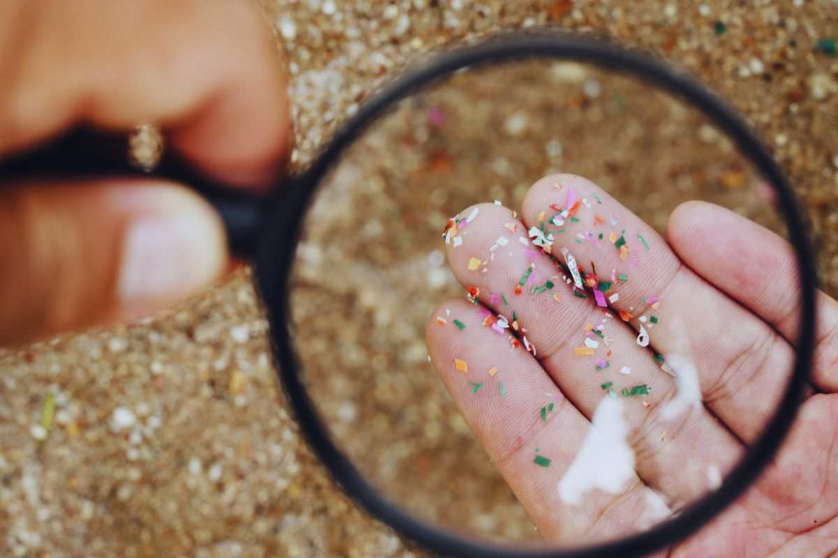 Persona che osserva le microplastiche con la lente d'ingrandimento