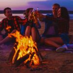 Coppie che brindano davanti al falò in spiaggia