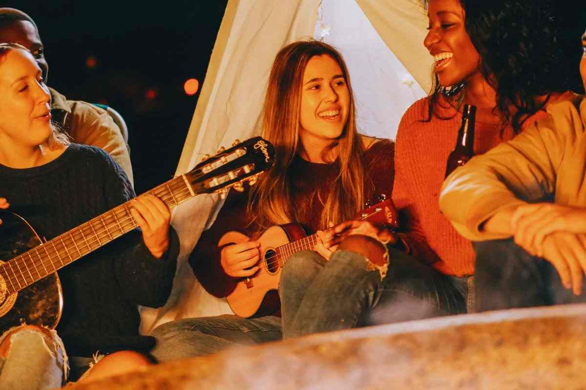 Ragazze che suonano chitarra davanti a falò