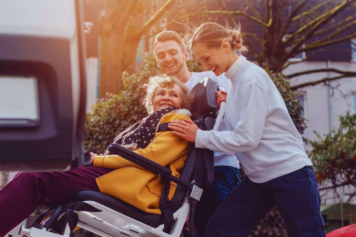 Persone che aiutano una disabile a salire su un veicolo