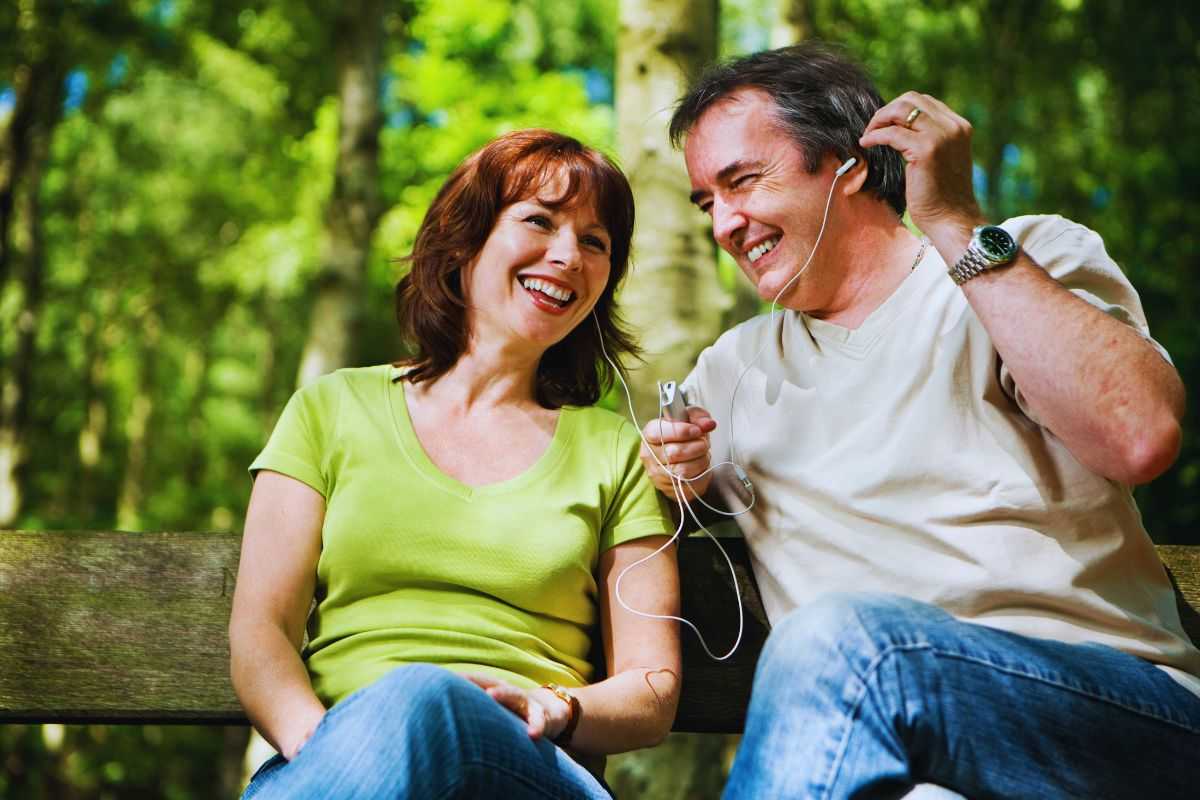 Coppia adulta che ascolta musica in un parco