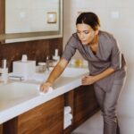 Donna che pulisce lavabo bagno