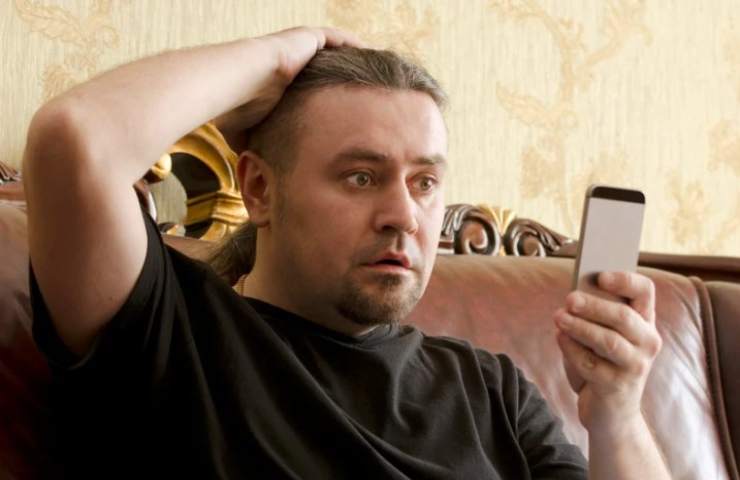 Uomo guarda il telefono sconvolto