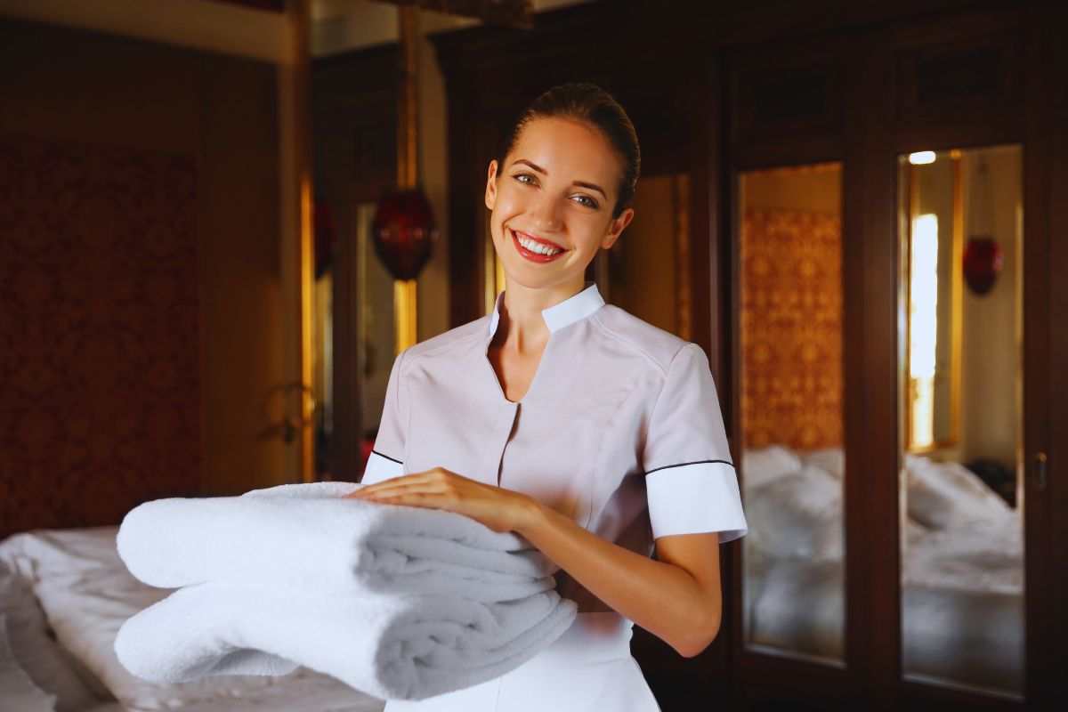 Cameriera sorridente che cambia le tovaglie del bagno