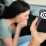 donna con nausea e smartphone tenuto in mano