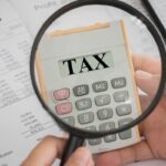 Lente di ingrandimento inquadra calcolatrice con scritto "Tax"