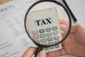 Lente di ingrandimento inquadra calcolatrice con scritto "Tax"