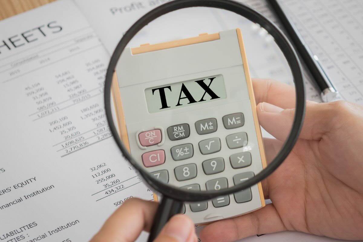 Lente di ingrandimento inquadra calcolatrice con scritto "Tax"