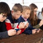 Bambini intenti ad osservare gli schermi del telefono