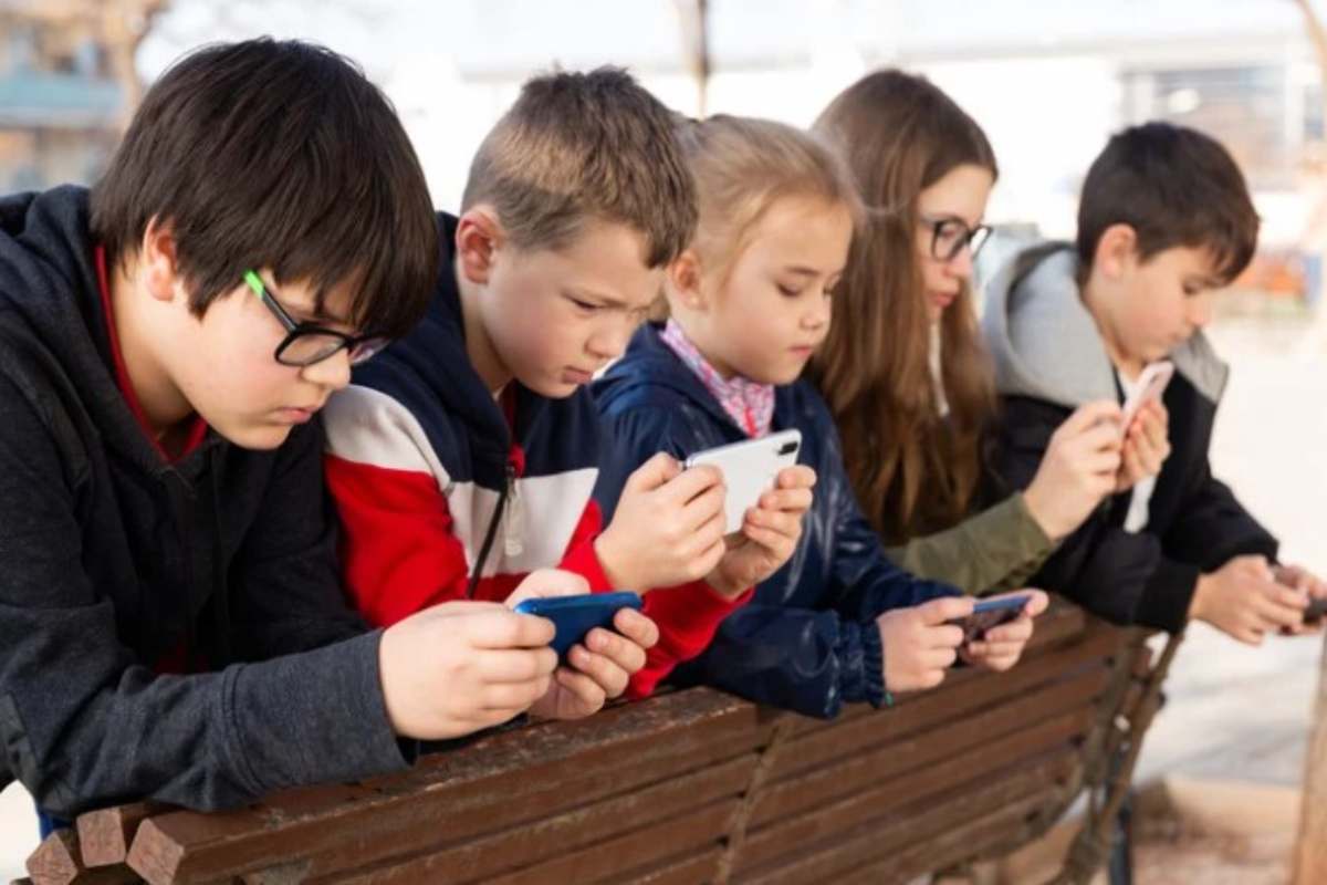 Bambini intenti ad osservare gli schermi del telefono