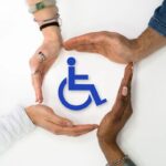 Mani attorno a simbolo disabilità