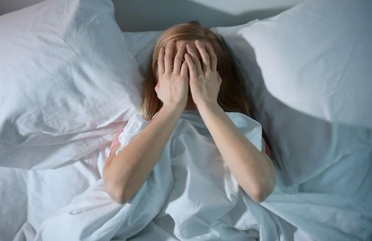 Donna a letto con le mani sul viso  non riesce a dormire 